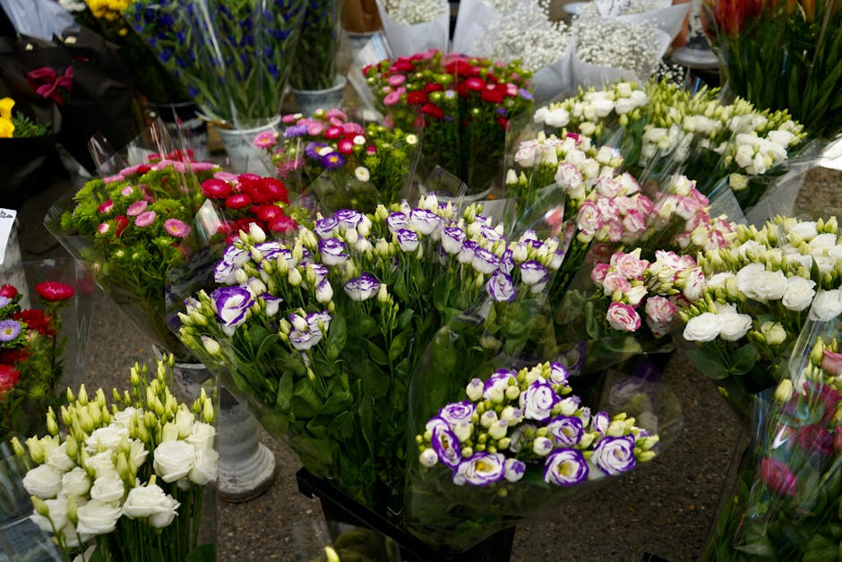 A variety of fresh floral arrangements displayed on a table, featuring assorted flowers including purple and white lisianthus, pink and white roses, and small pink, red, purple, and white daisies, all